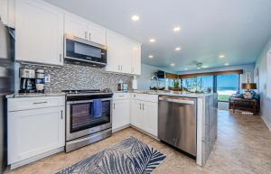 una cocina con armarios blancos y electrodomésticos de acero inoxidable en Beachfront Aldea 11 en Clearwater Beach