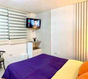 a bedroom with a purple bed and a tv on the wall at Cusco Magico 9 - Loft Santa Ursula in Cusco
