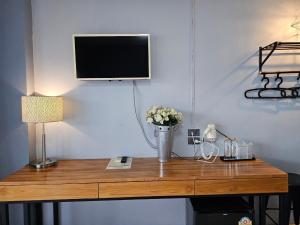 a wooden table with a tv on a wall with a desk at Phusuang Place in Chiang Mai