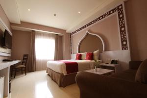 ein Hotelzimmer mit einem Bett und einer Couch in der Unterkunft Namira Syariah Hotel Surabaya in Surabaya + 37 Fotos