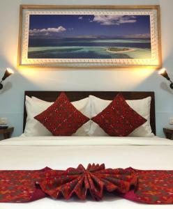 a bed with red pillows and a painting on the wall at Wae Molas Hotel in Labuan Bajo