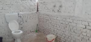 a bathroom with a toilet and a white brick wall at Baba hostel in Pushkar +20 photos