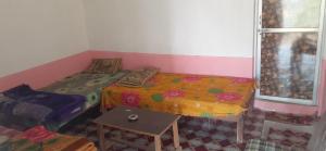 Habitación con 2 camas y mesa. en Baba hostel en Pushkar