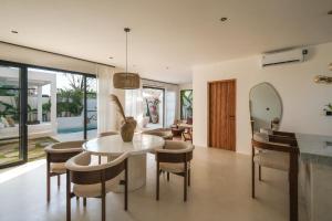 a dining room and living room with a table and chairs at Villa Sama Canggu in Canggu