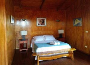 1 dormitorio con 1 cama en una habitación de madera en Atavai Hotel Rapa Nui en Hanga Roa