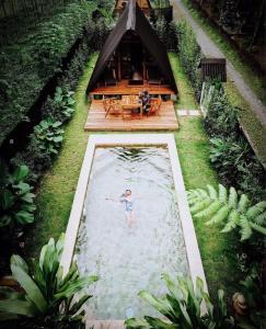 a man swimming in a pool in front of a house at Villa Verde the garden in Kejayan