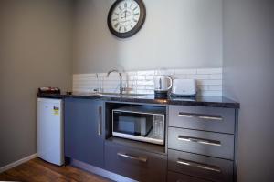a kitchen with a microwave and a clock on the wall at THE Residence Apartment 8 50 Sky in New Plymouth