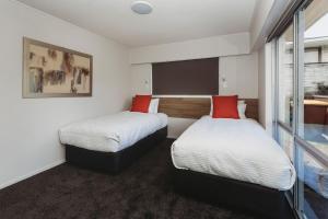 a hotel room with two beds with red pillows at Love It On Lemon in New Plymouth