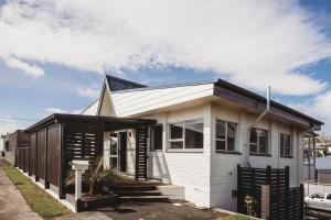 a small white house with a black roof at Love It On Lemon in New Plymouth