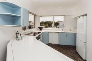a kitchen with white counters and blue cabinets at Blue Haven On Belt Waterfront in New Plymouth