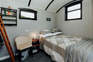 a small bedroom with a bed and a chair at Onaero s Quaint Little Cottages in Waitara