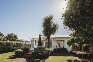 ein Haus mit einer Palme im Hof in der Unterkunft Ropiha Retreat Close To Fitzroy Beach in New Plymouth