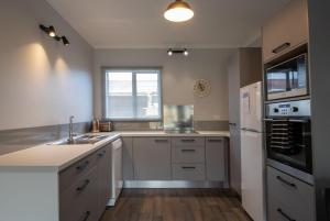 a kitchen with a sink and a refrigerator at The Flight Pad Window Seat Pet Friendly in Waitara