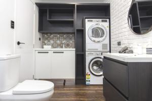 a bathroom with a toilet and a washer and dryer at Chic IN THE City in New Plymouth