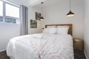 1 dormitorio blanco con 1 cama grande con almohadas blancas en Chic IN THE City, en New Plymouth