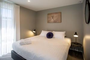 een slaapkamer met een groot wit bed met witte kussens bij The Residence Apartment Five with Spa Bath in New Plymouth