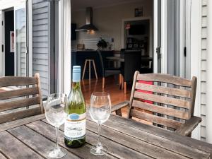 a bottle of wine sitting on a wooden table with two glasses at The Brooklands Bungalow in New Plymouth