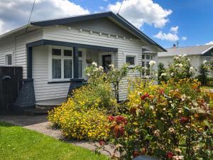 a white house with flowers in front of it at The Brooklands Bungalow in New Plymouth