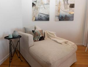 a white couch in a living room with three paintings at Fox Lodge Central Location in New Plymouth