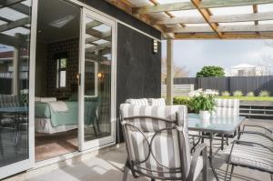 eine Terrasse mit einem Tisch und Stühlen sowie ein Schlafzimmer in der Unterkunft Relax On Richmond Modern Large Beach House in New Plymouth