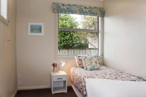a small bedroom with a bed and a window at Relax On Richmond Modern Large Beach House in New Plymouth