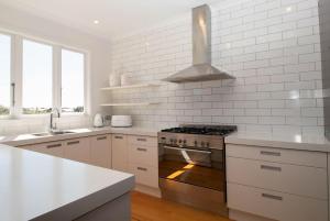 a white kitchen with a stove and a sink at Fox Lodge Central Location in New Plymouth