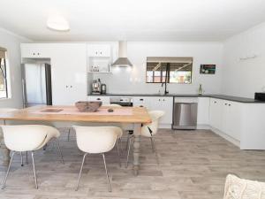 uma cozinha com uma mesa de madeira e cadeiras brancas em Aqua Vista On Arden - Support Local em Oakura