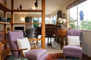 a living room with a grand piano and chairs at Memories On Mcfarlane Prime Oakura Location in Oakura