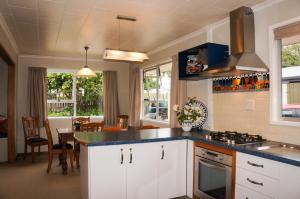 een keuken met witte kasten en een eetkamer bij Memories On Mcfarlane Prime Oakura Location in Oakura