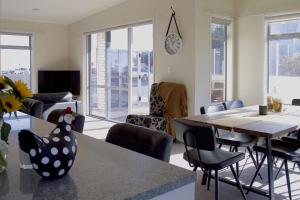 a living room with a table and chairs and a clock at Escape To Buller Prime Holiday Location in New Plymouth