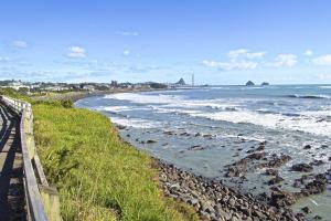 a beach with a fence and the ocean at Escape To Buller Prime Holiday Location in New Plymouth