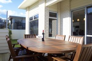 a wooden table with a bottle of wine on a patio at Escape To Buller Prime Holiday Location in New Plymouth