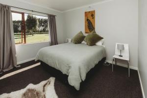 a bedroom with a large bed and a window at Wharepuni Oakura Retreat in Tataraimaka