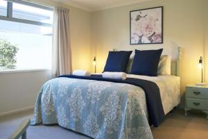a bedroom with a bed with blue pillows and a window at Escape To Buller Prime Holiday Location in New Plymouth