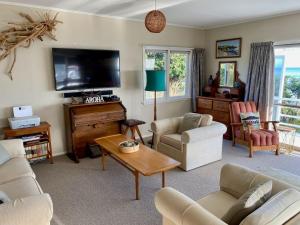 sala de estar con sofá y TV en Messenger Magic A Classic Kiwi Bach, en Oakura