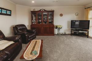 a living room with leather furniture and a flat screen tv at Stay At Saddle Row in New Plymouth
