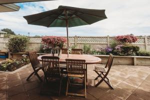 a table and chairs with an umbrella on a patio at Stay At Saddle Row in New Plymouth