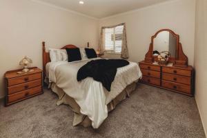 a bedroom with a bed and a dresser and a mirror at Stay At Saddle Row in New Plymouth