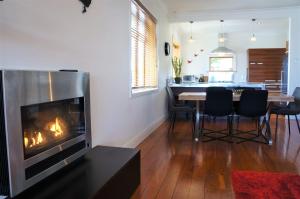 a living room with a fireplace and a table with chairs at The Buller Bungalow You Will Fall In Love in New Plymouth