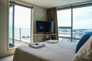 a bedroom with a bed with a tv and a large window at Luxury On Liardet in New Plymouth