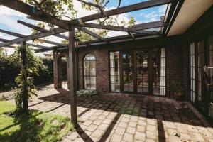 a brick house with a pergola on a patio at Family Fun Swimming Pool Spa Pool in New Plymouth