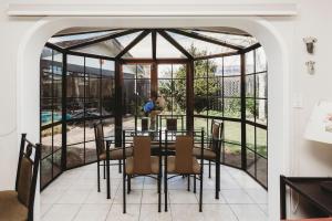 a dining room with a screened in porch with a table and chairs at Family Fun Swimming Pool Spa Pool in New Plymouth