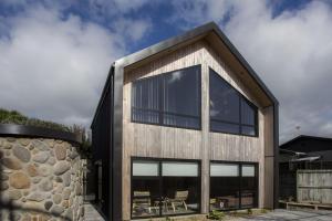 a modern house with a stone wall at The Natural Home Prime Fitzroy Location in New Plymouth