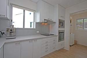 a white kitchen with white cabinets and a window at Quarterdeck 8 in Lennox Head