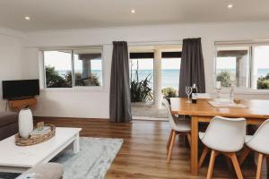 a living room with a dining room table with a view of the ocean at Wow On Wanaka Bay in New Plymouth