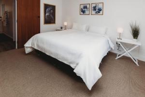a large white bed with a white blanket on it at Wow On Wanaka Bay in New Plymouth
