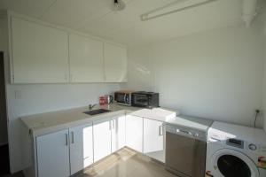 cocina con armarios blancos y microondas en Wills On The Water Beachfront Apartment, en Bell Block