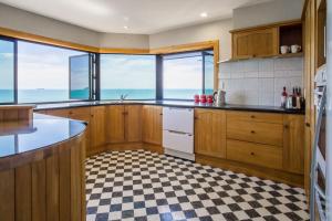 a kitchen with wooden cabinets and a checkered floor at Waterfront On Woolcombe in New Plymouth