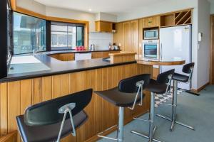 a kitchen with black bar stools and a counter at Waterfront On Woolcombe in New Plymouth
