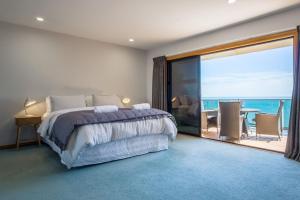 a bedroom with a bed and a view of the ocean at Waterfront On Woolcombe in New Plymouth